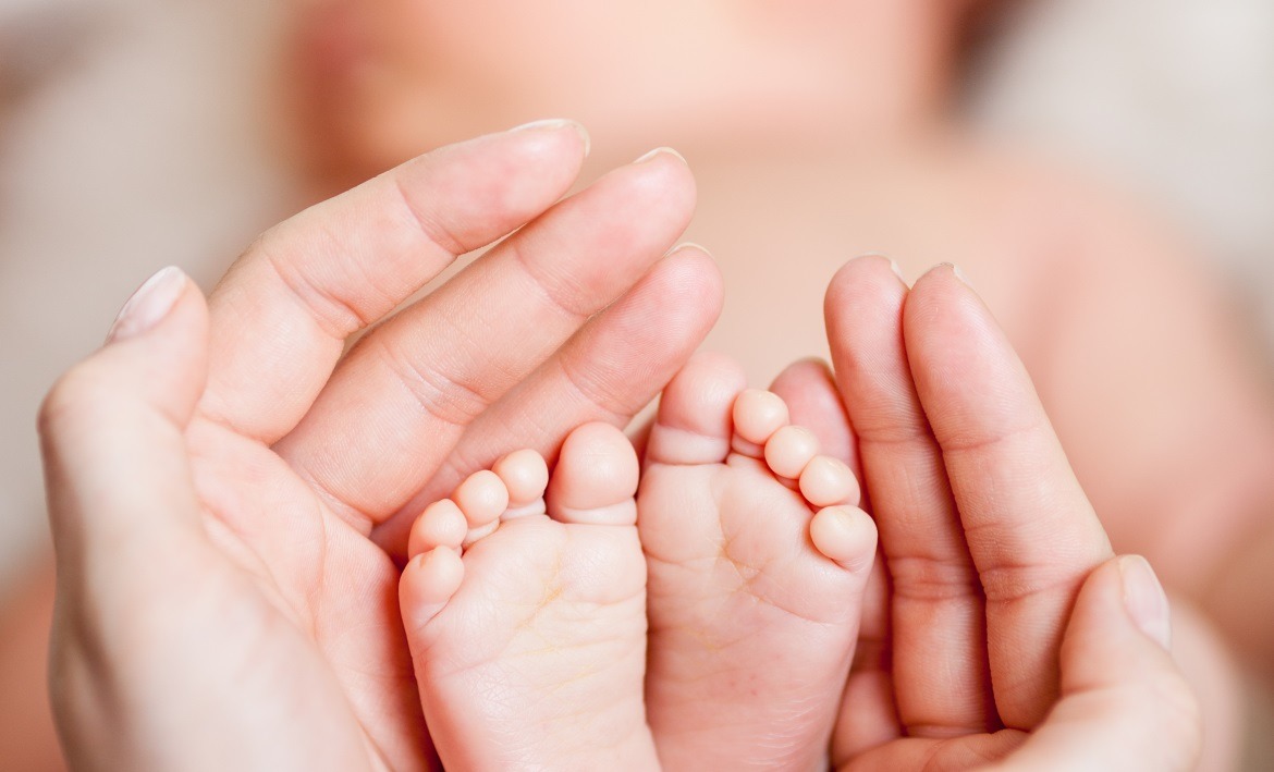 Fertility Massage - baby feet enclosed in parents hands